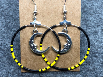 Black and yellow beaded hoop earrings with man in the moon charm. Black and yellow beaded hoop earrings with man in the moon charm.